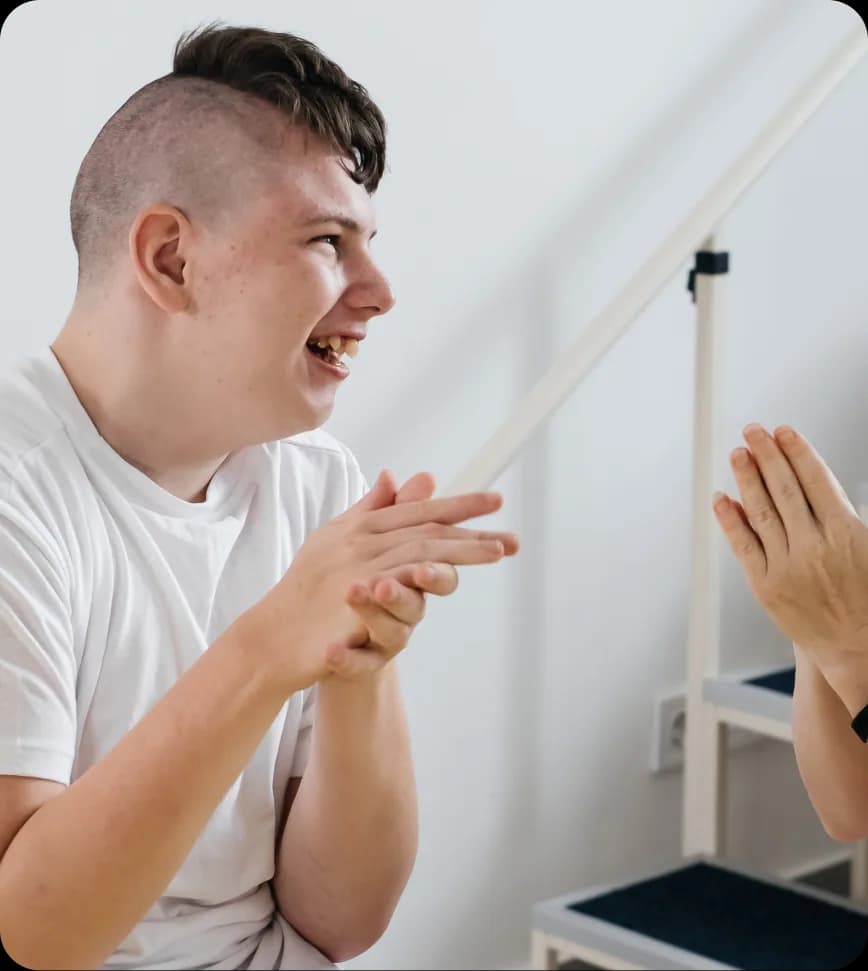 Een lachende jongere klapt in de handen met iemand tegenover zich.